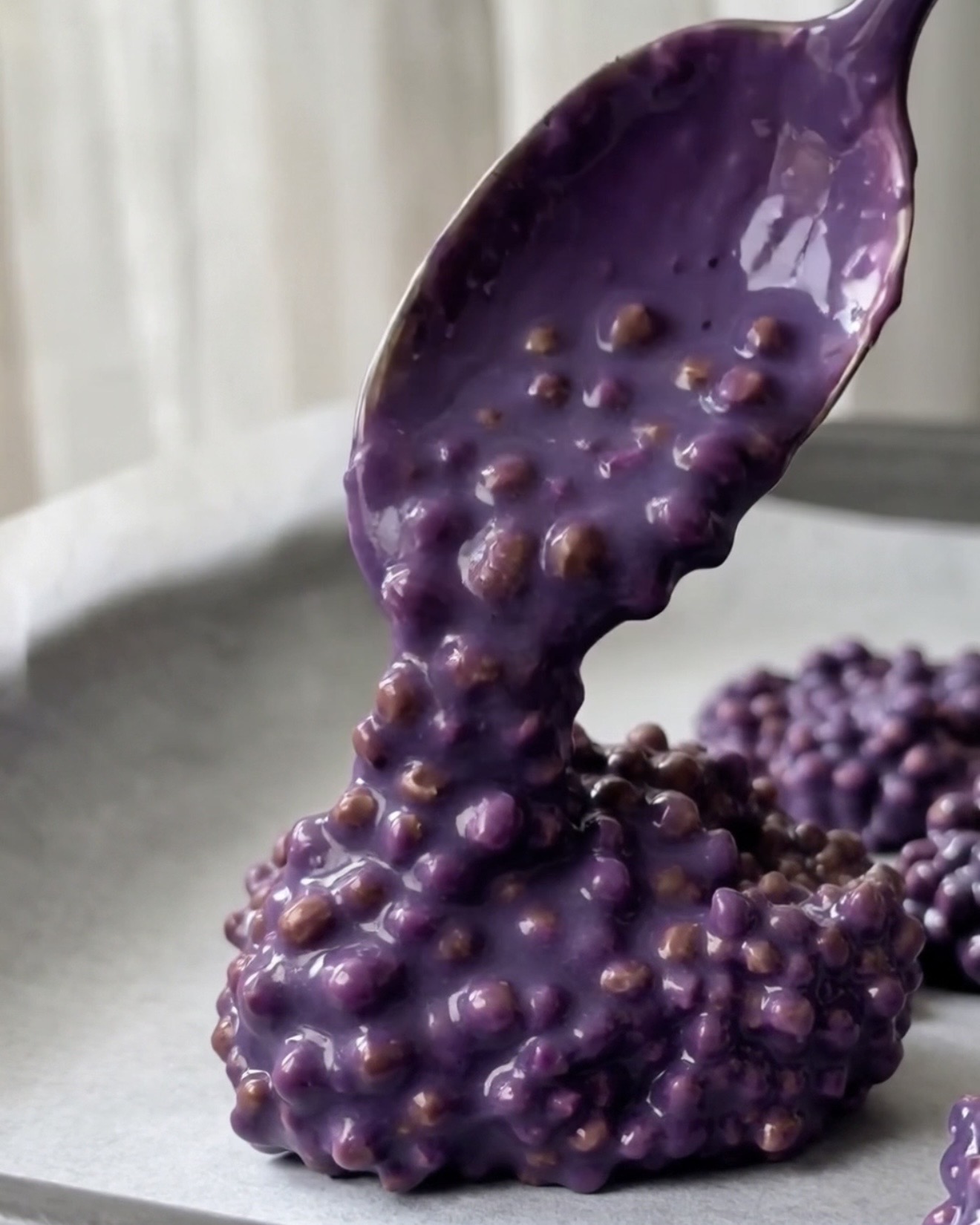 Cucharadas de mezcla de quinoa ube en discos sobre papel de horno para bocaditos de quinoa ube y pistacho Ube Nolia