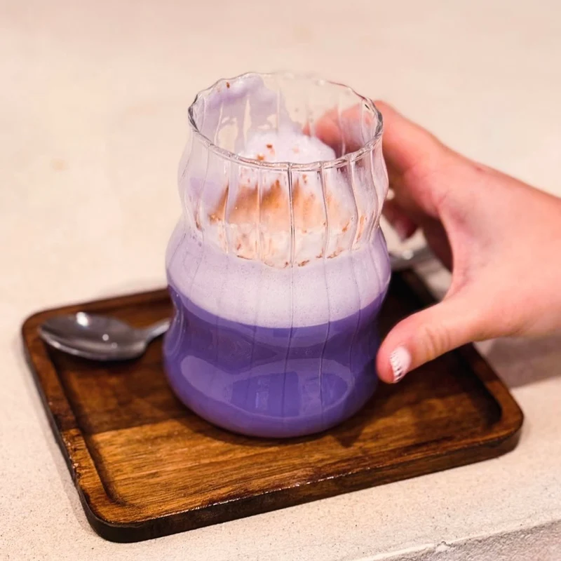 Ube Latte de Ube Nolia en un vaso estriado sobre una bandeja de madera