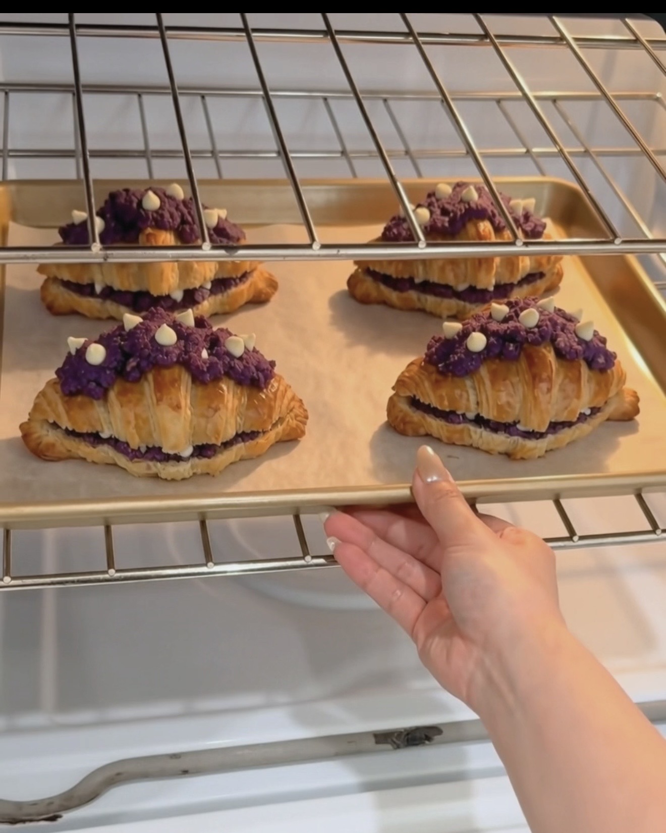 Bandeja de Ube Nolia ube crookies recién salidos del horno con capas doradas de cruasán y cobertura de galleta de ube (ñame morado) morada con chispas de chocolate blanco