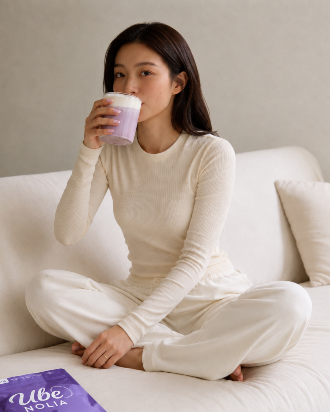 Mujer bebiendo un Ube Latte de Ube Nolia junto a la bolsa de polvo de ube