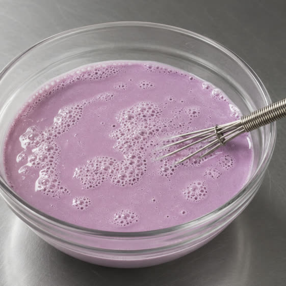 Mezcla de leches de ube violeta batida en un bol de cristal | Ube Nolia