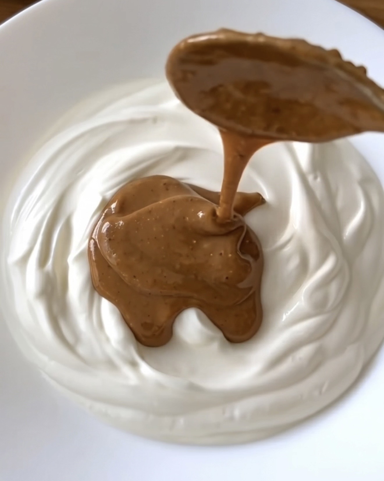 Mantequilla de cacahuete vertida sobre yogur griego cremoso para los bocaditos helados de yogur de ube de Ube Nolia