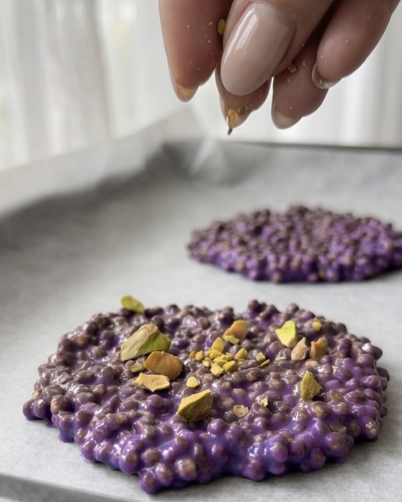 Pistachos triturados cubriendo bocaditos de quinoa ube morada de Ube Nolia