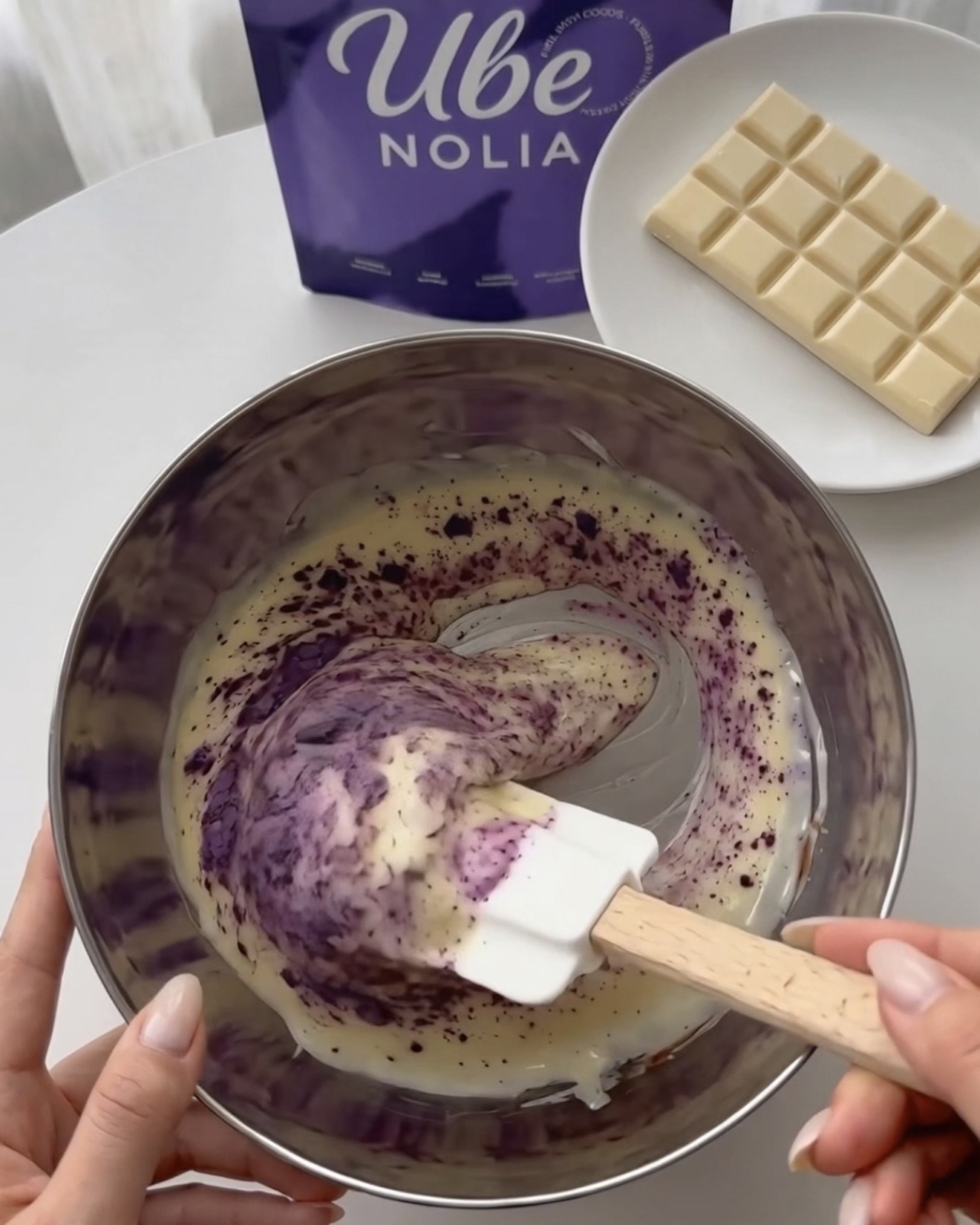Incorporando Ube Nolia polvo de ube en chocolate blanco derretido para bocaditos de quinoa morada y pistacho