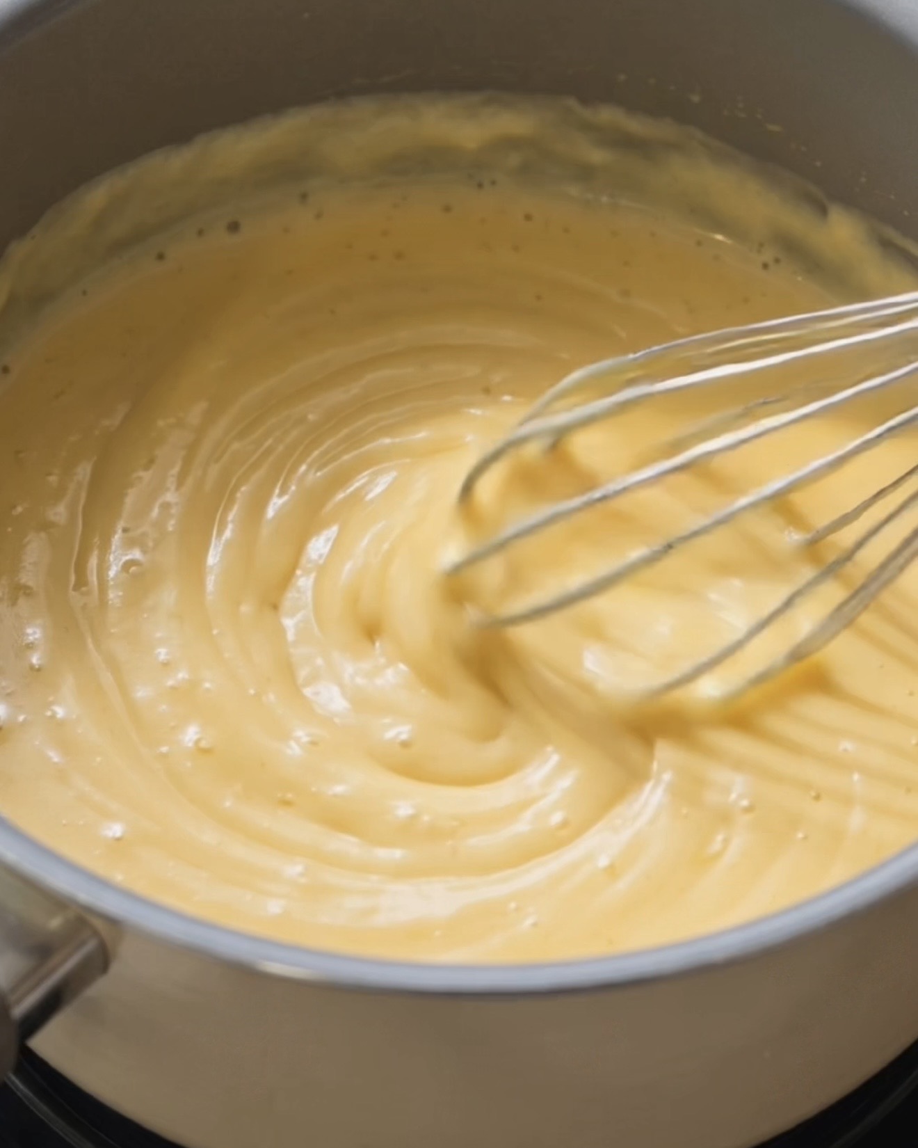 Leche de coco y leche condensada calentándose juntas para hacer la base del relleno de ube halaya para ube dadar gulung