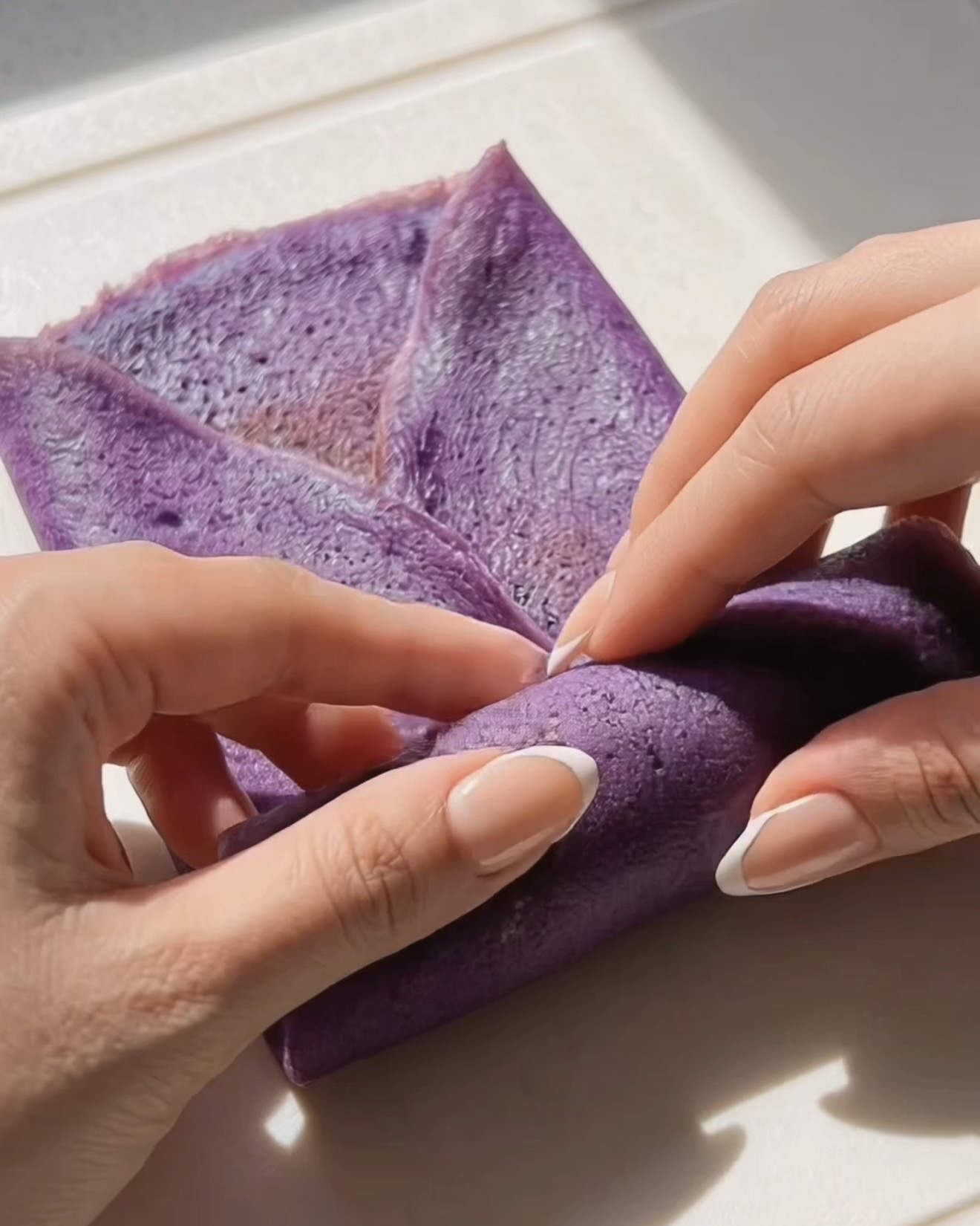 Enrollando un crepe de ube dadar gulung estilo sobre alrededor del relleno de ube halaya morado