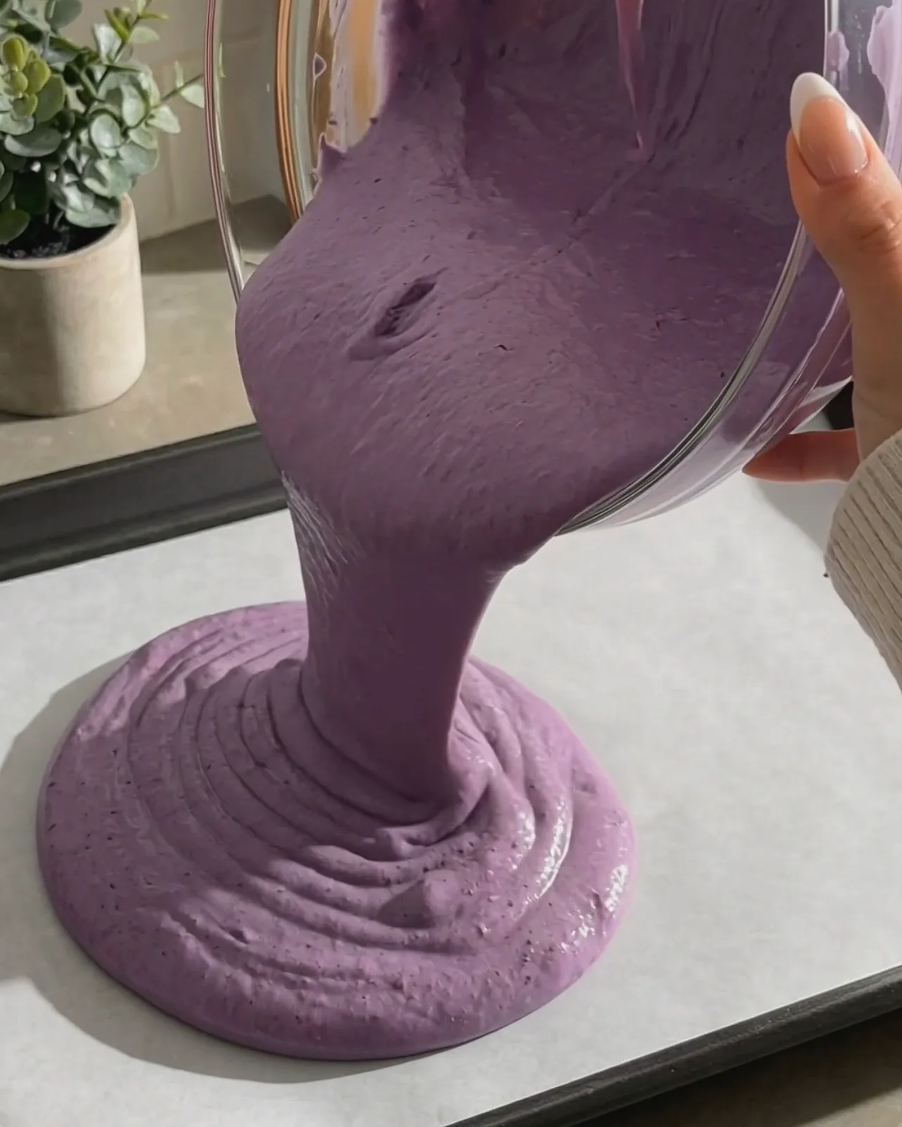 Vertiendo la vibrante masa morada de bizcocho chiffon de ube en una bandeja de horno forrada con papel de horno de Ube Nolia