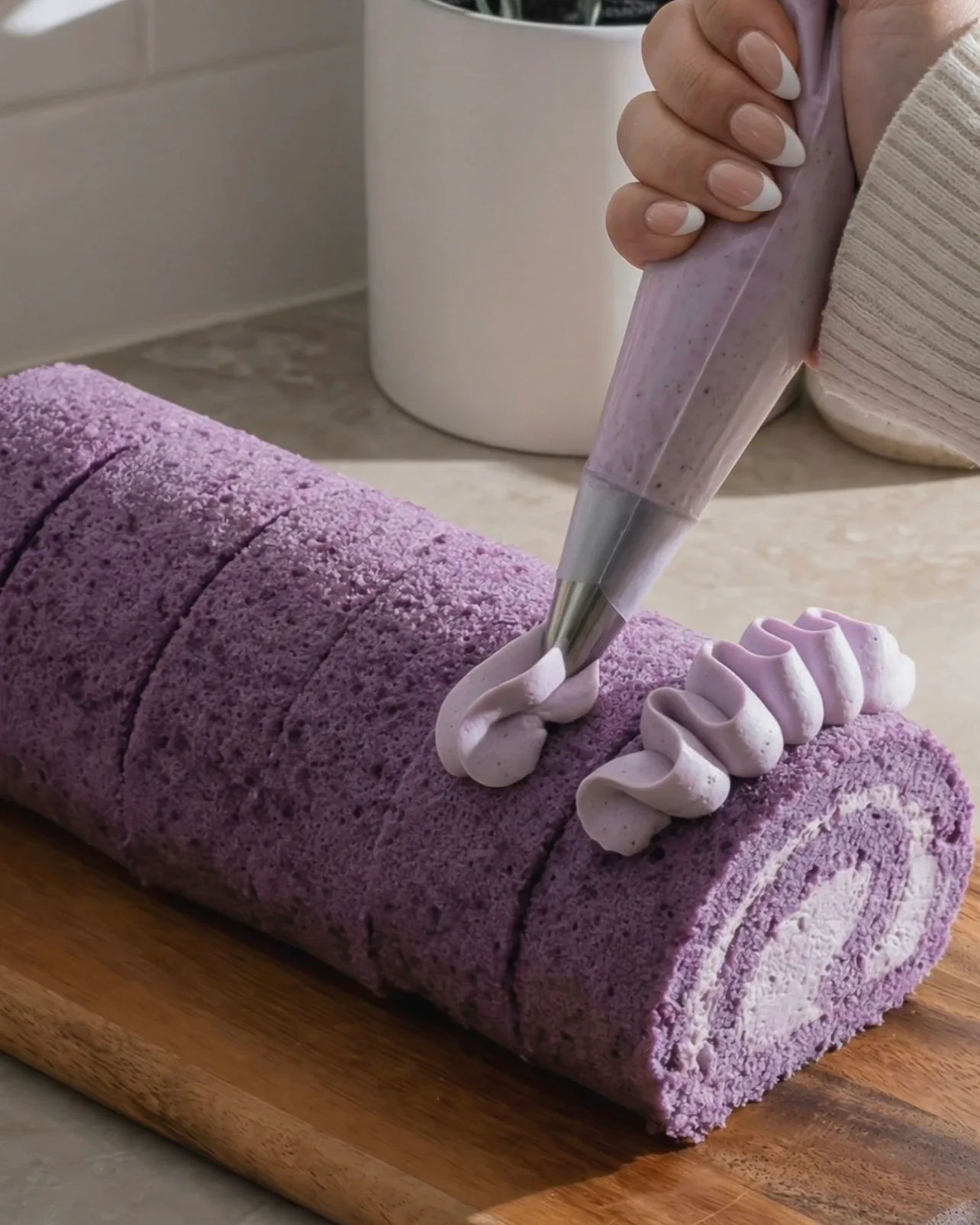 Decorando con rosetas de crema batida de ube sobre el brazo de gitano morado terminado de Ube Nolia