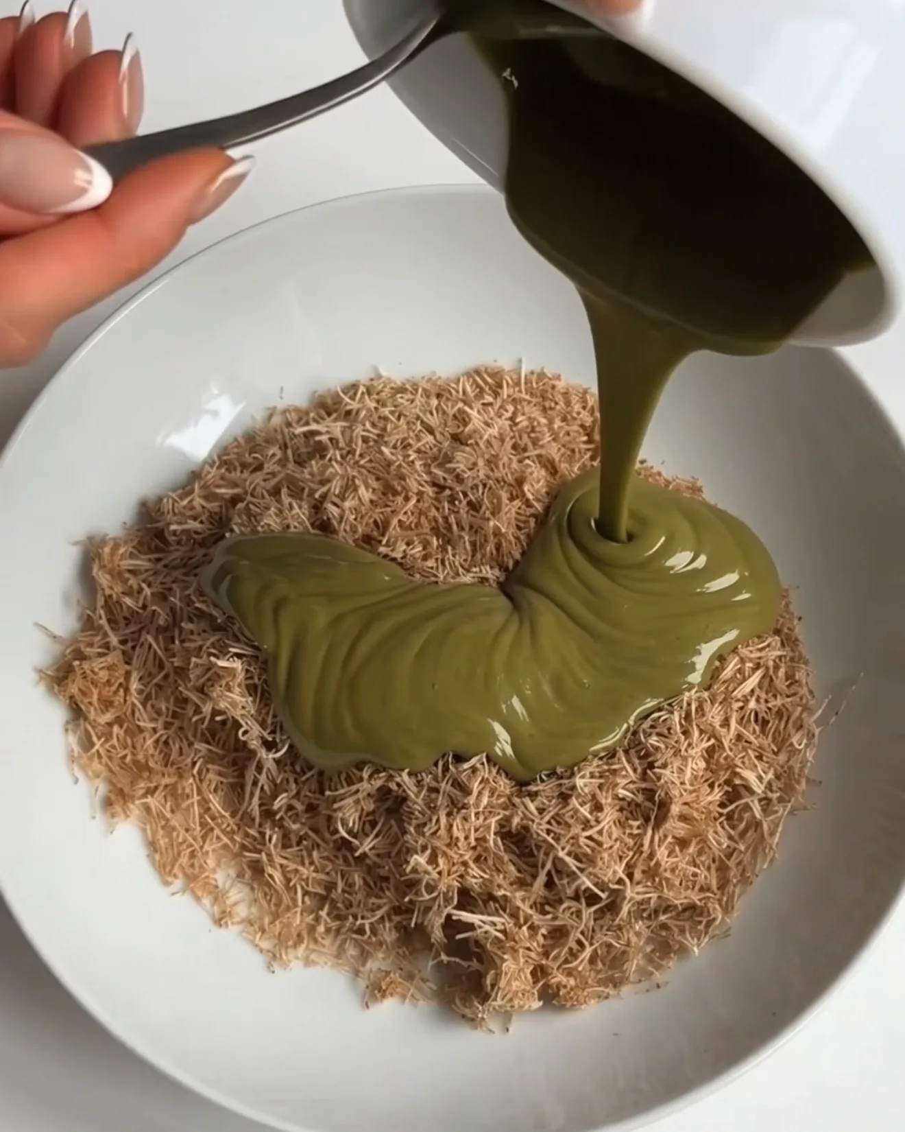 Crema de pistacho vertida sobre un bol de pasta kataifi tostada para el relleno de las barras de brownie de chocolate Ube Dubái de Ube Nolia